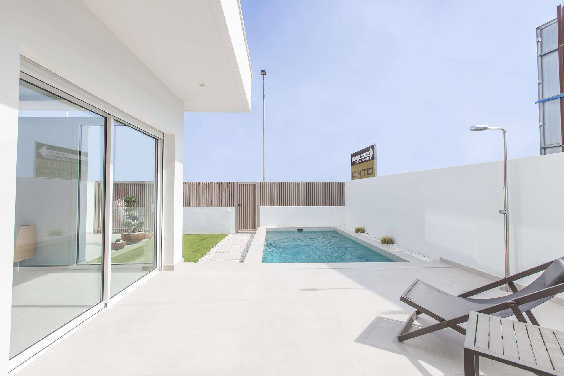 Sonnige Terrasse mit kleinem Pool, Liegestühlen und großen Glasschiebetüren zum Innenbereich.