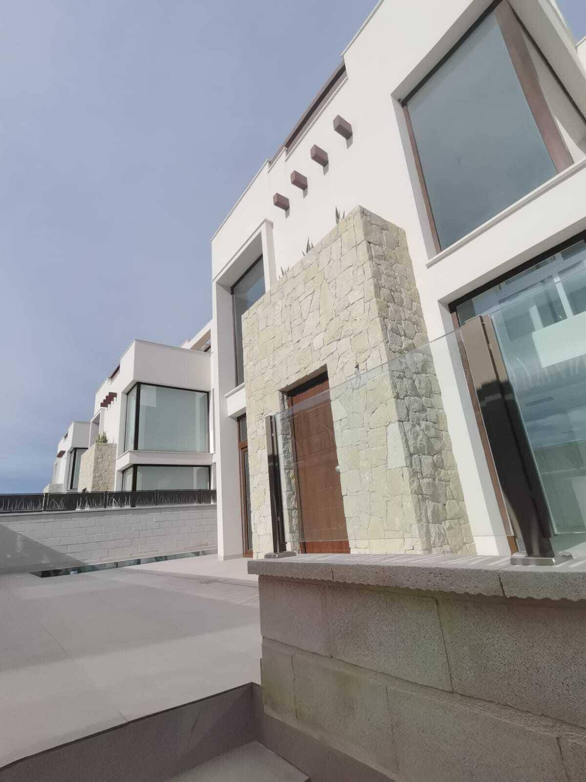 Moderne Architektur mit weißer Fassade und großen Glasflächen neben dem privaten Poolbereich.
