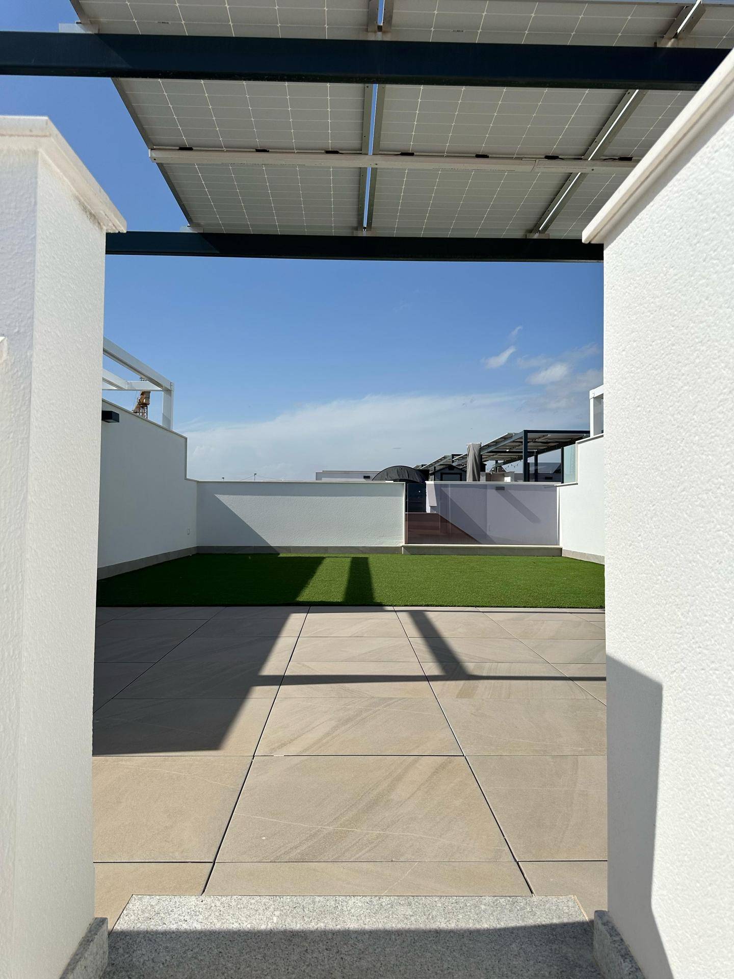 Geräumige Dachterrasse mit Kunstrasen, Fliesenboden und Solarpaneelen für nachhaltiges Wohnen.