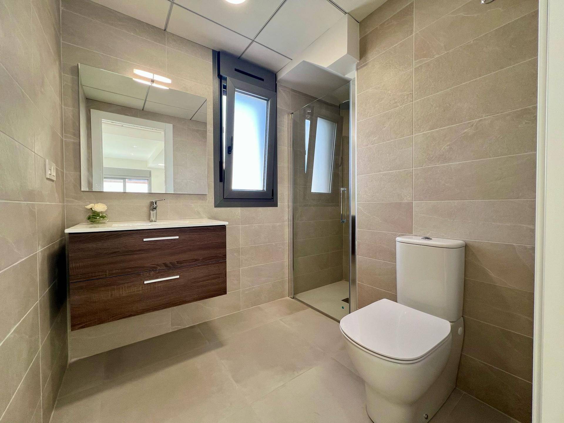 Modernes Badezimmer mit begehbarer Dusche, schwebendem Waschtisch und Fenster für Tageslicht.