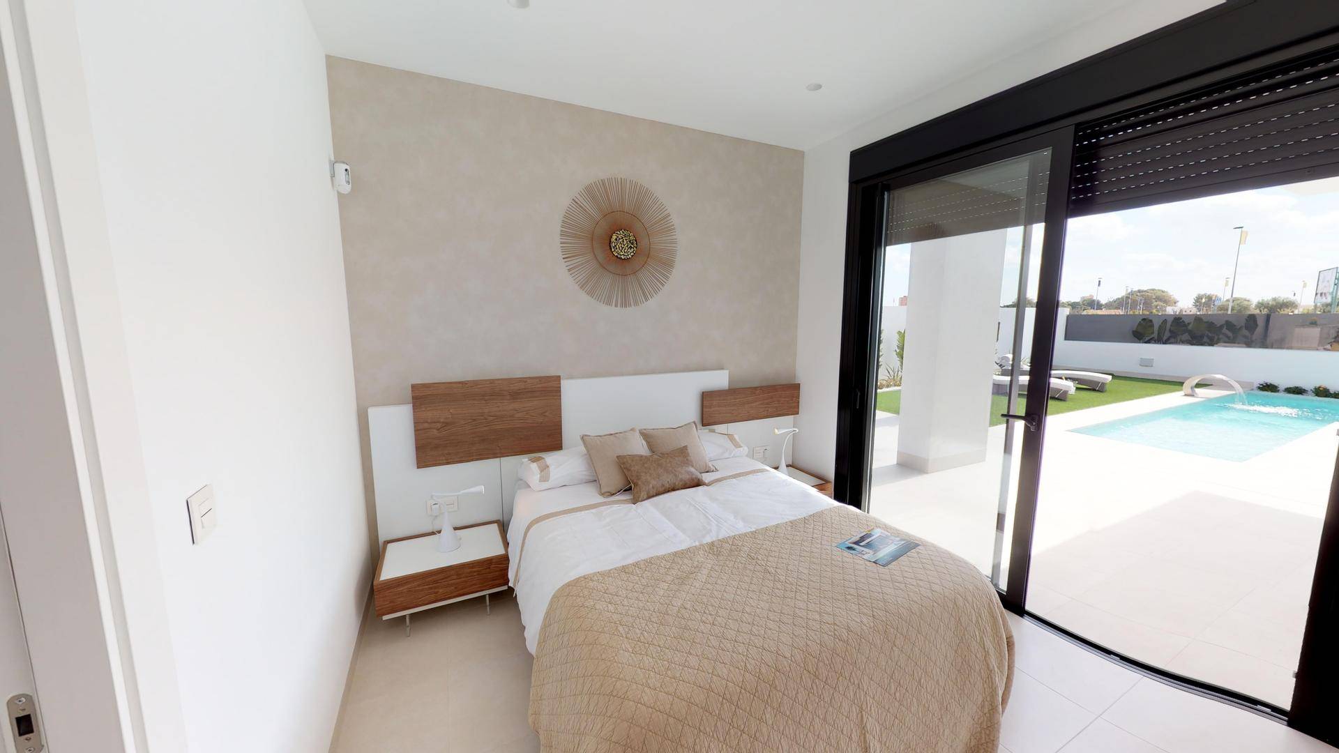 Modernes Schlafzimmer mit direktem Zugang zum Poolbereich und großen Schiebetüren.