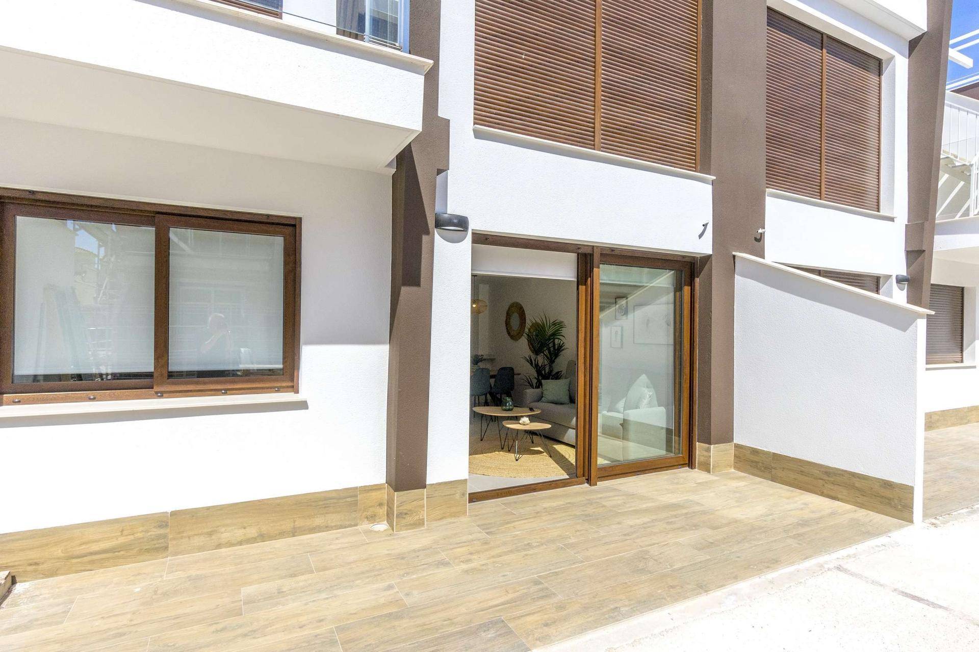 Erdgeschoss-Terrasse mit großen Glasschiebetüren, die zum hellen Wohnbereich führen.