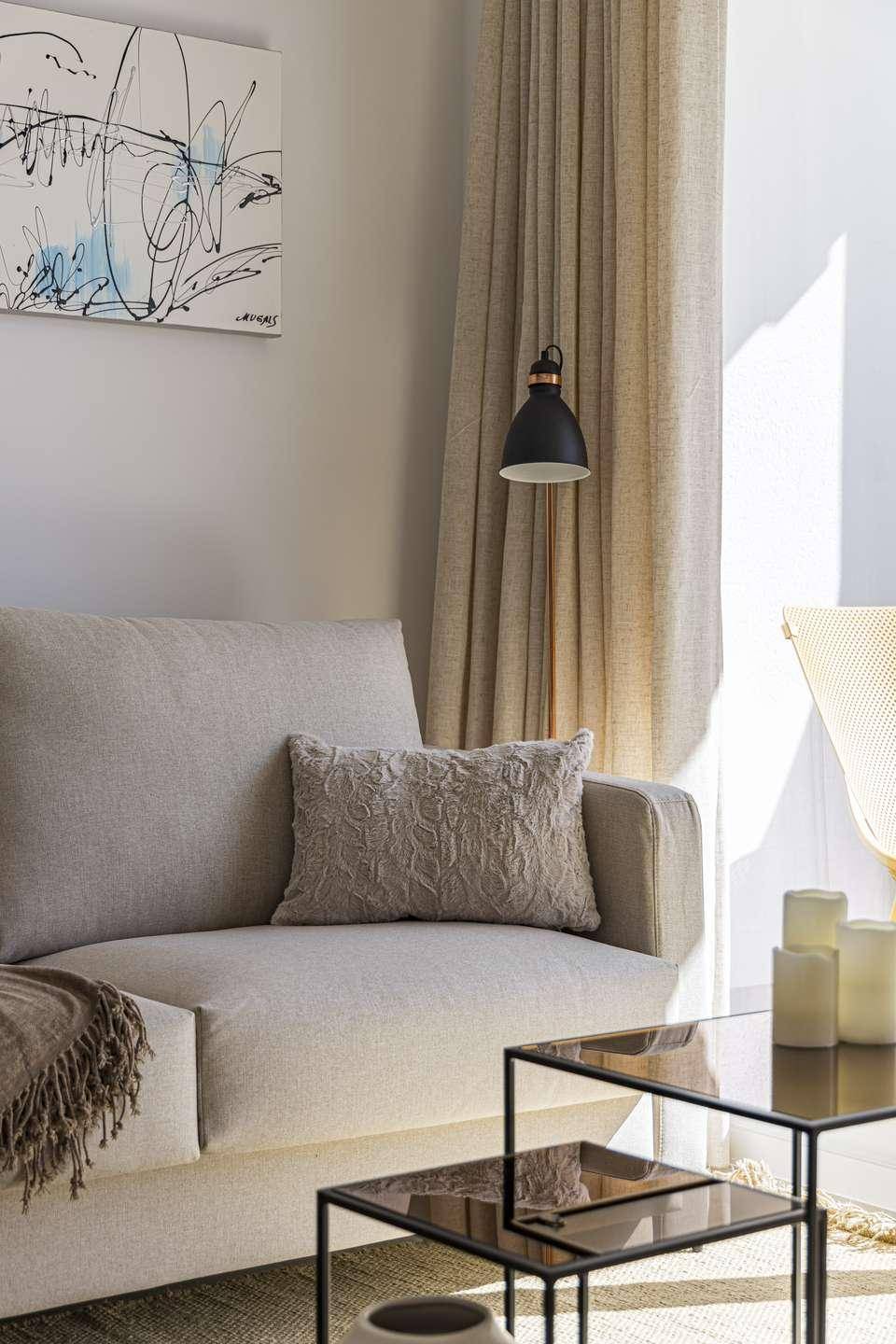 Gemütliche Sitzecke im Wohnzimmer mit hellem Sofa, modernen Beistelltischen und Stehlampe.