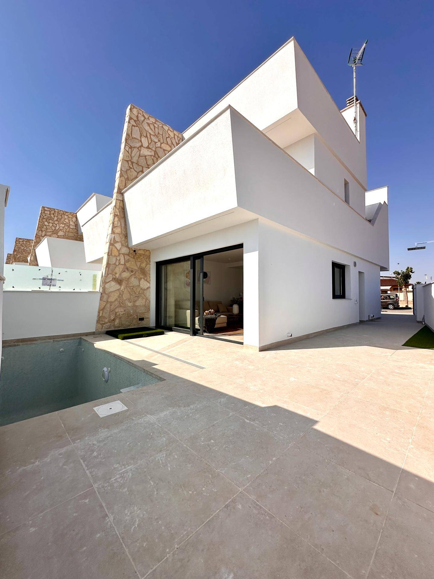 Neubau-Villa mit modernem Design, privatem Pool und sonniger Terrasse unter klarem Himmel.