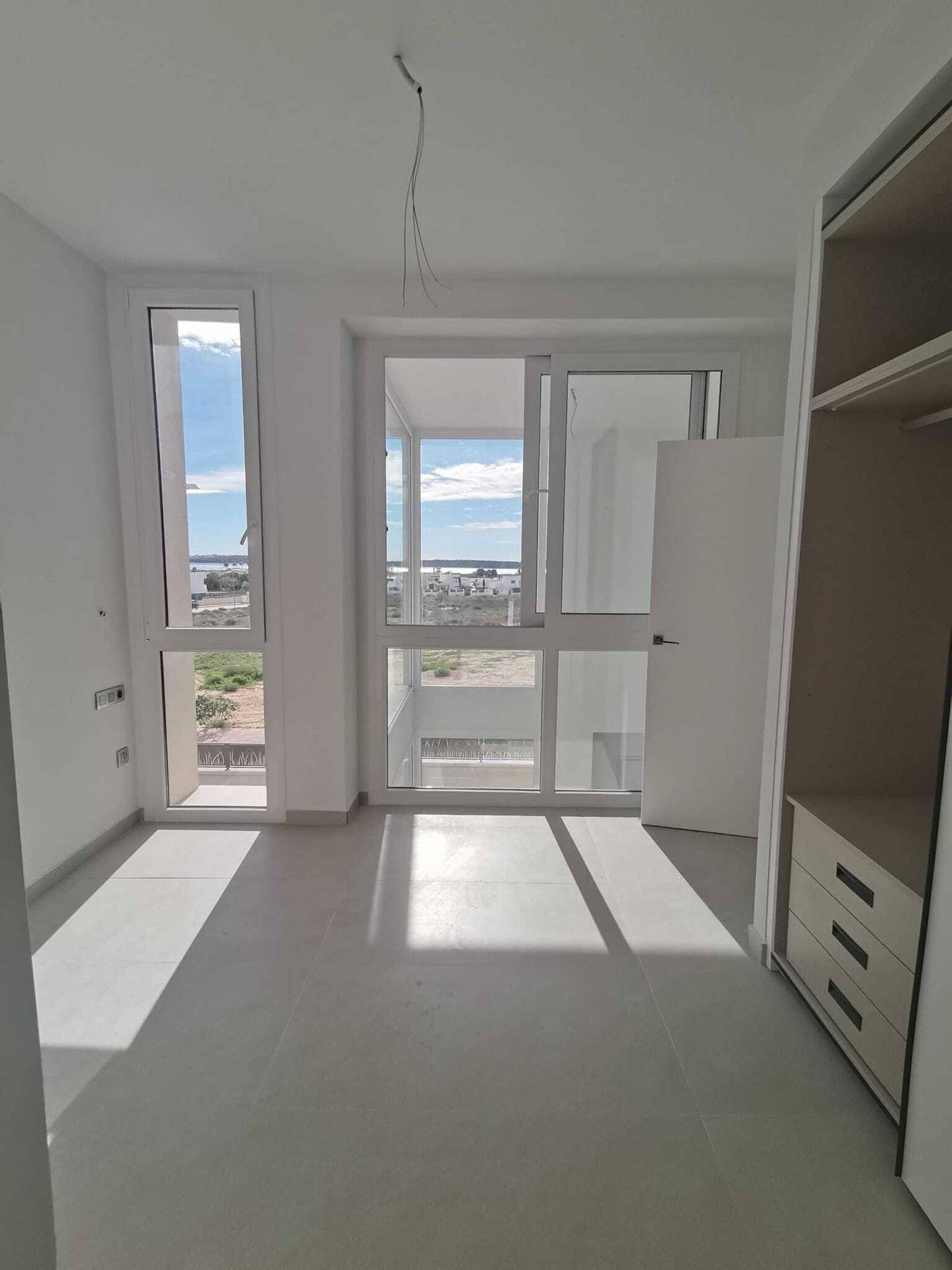 Helles Schlafzimmer mit Zugang zum Balkon und Einbauschrank, bereit zur Einrichtung und Nutzung.