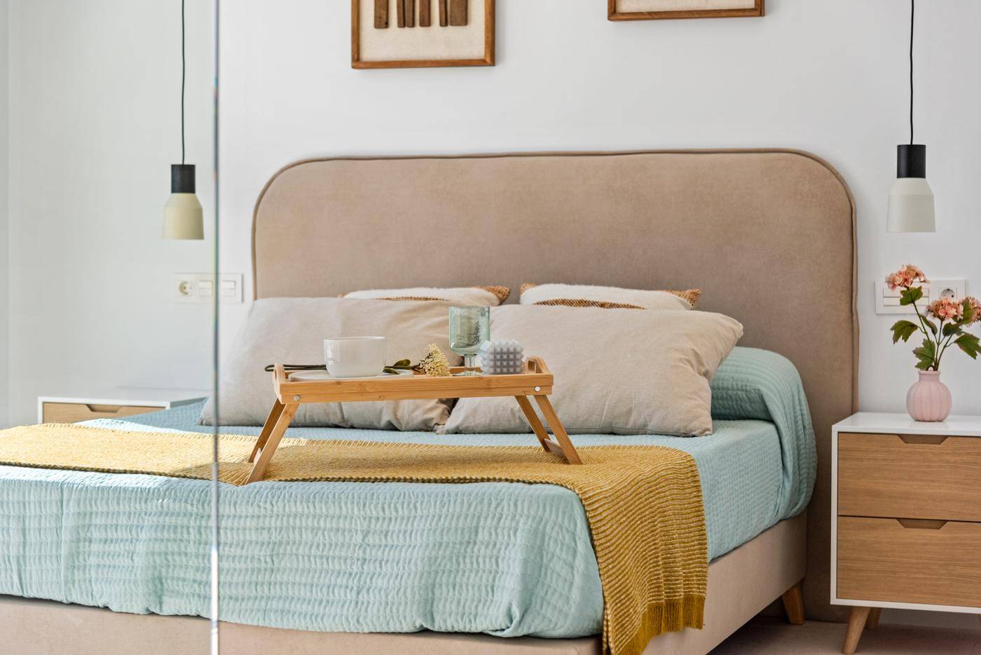 Helles Schlafzimmer mit Doppelbett, Nachttischen und Blick auf den Außenbereich.