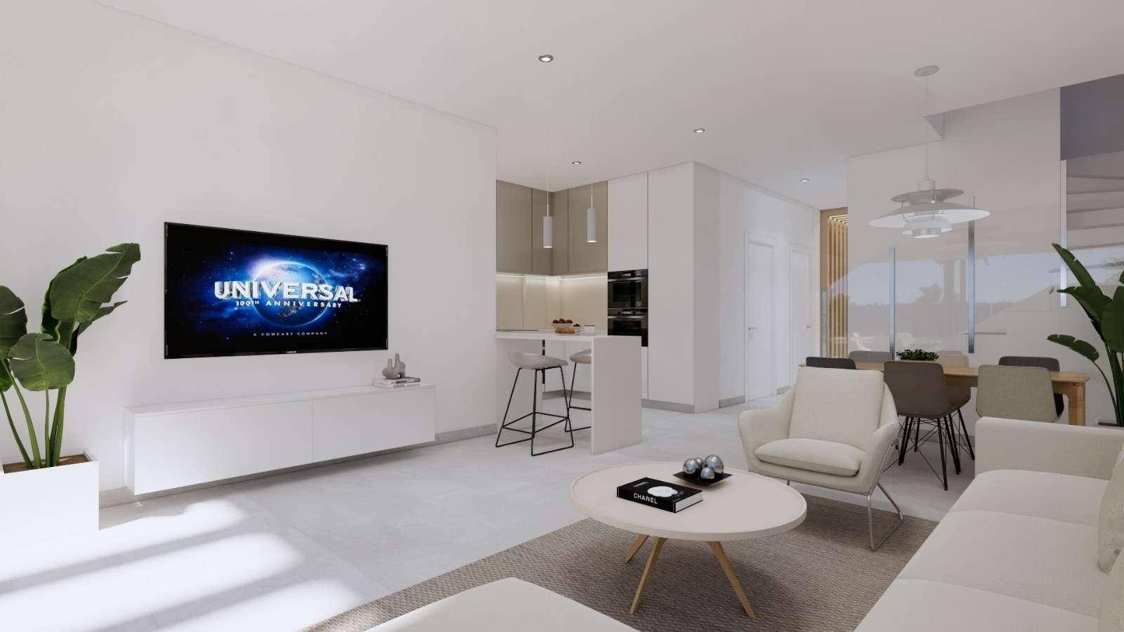 Offener Wohn-Essbereich mit moderner weißer Küche, Insel und gemütlichem Wohnbereich mit Fernseher.