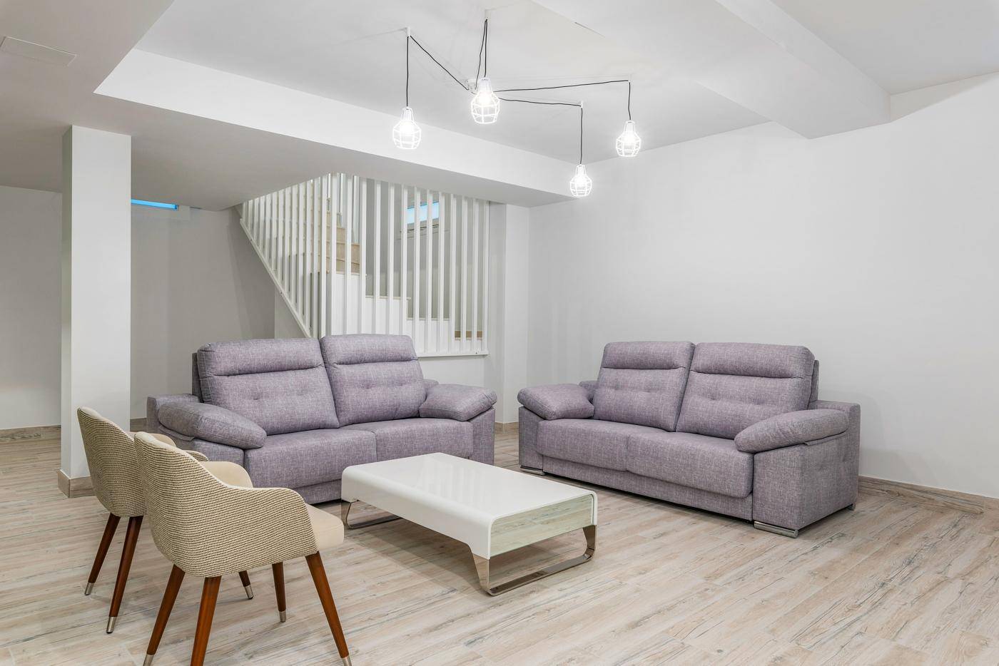 Heller Kellerraum, als Wohnbereich genutzt, mit bequemen Sofas und einer Treppe.