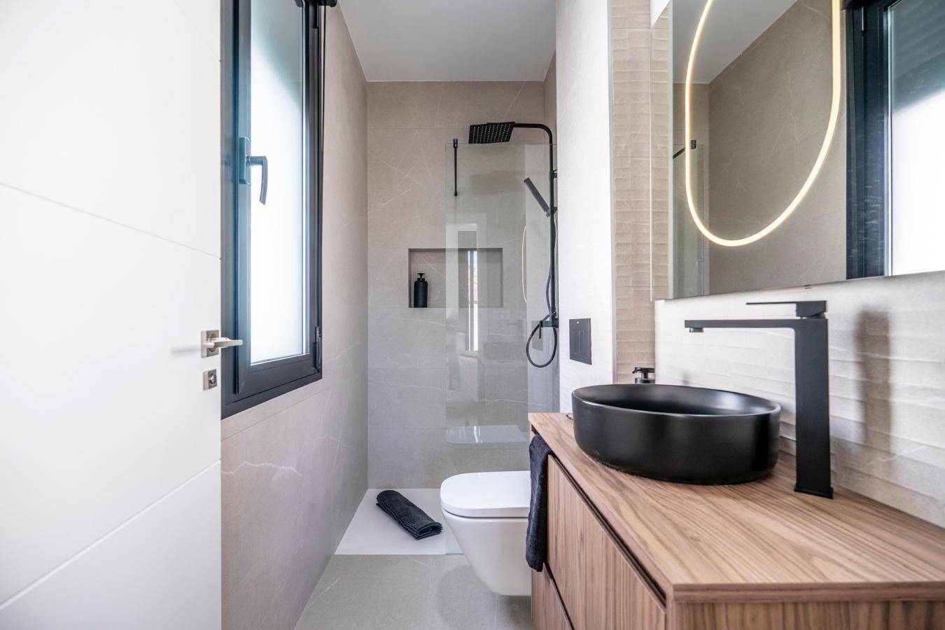 Stilvolles Badezimmer mit schwarzem Waschbecken, Holzunterschrank, wandhängendem WC und Fenster.
