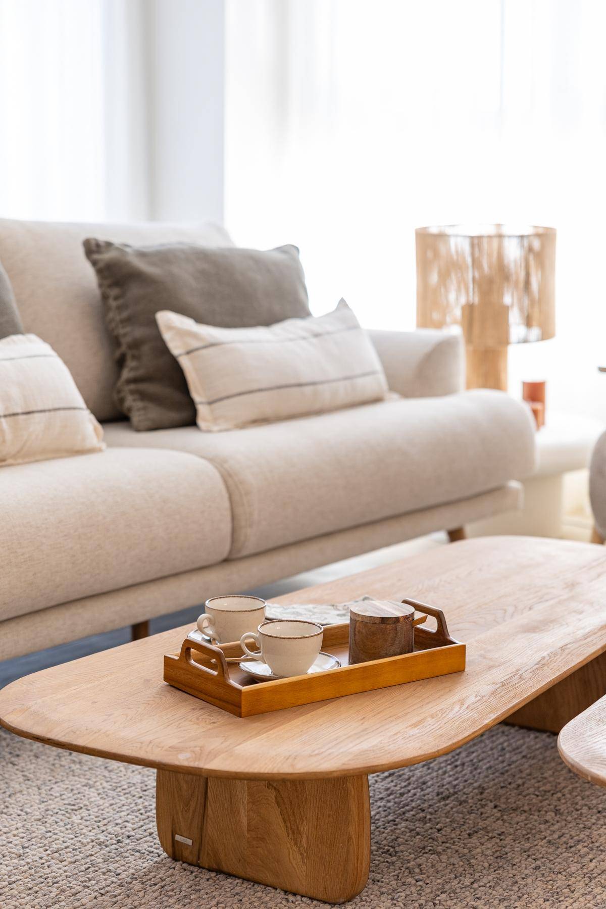Nahaufnahme des beigen Sofas und eines Holztisches mit einer Teetasse und Dekoration.