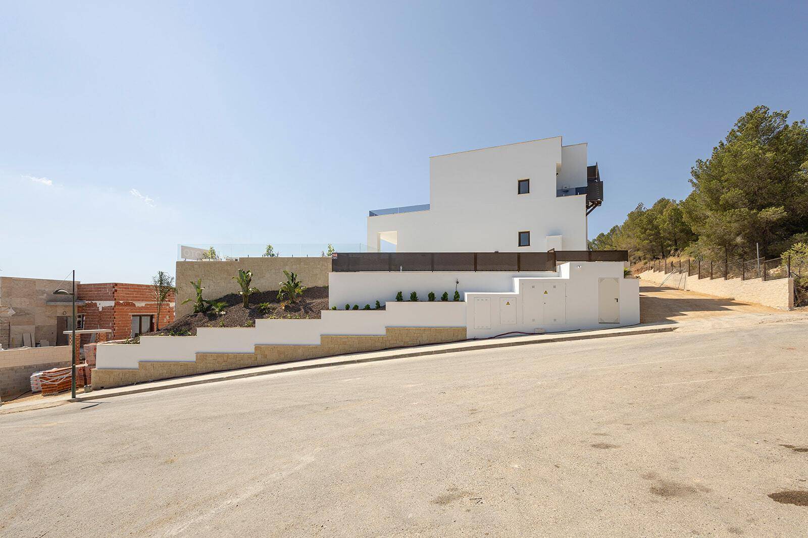Moderne Villa an einem Hang mit gestuften Terrassen und Blick auf die Umgebung.