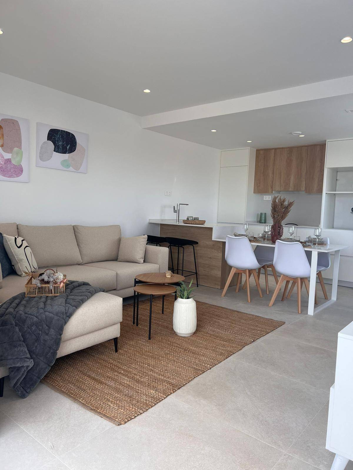 Geräumiger Wohn-Essbereich mit beigem Sofa, Teppich und Blick auf die offene Küche.