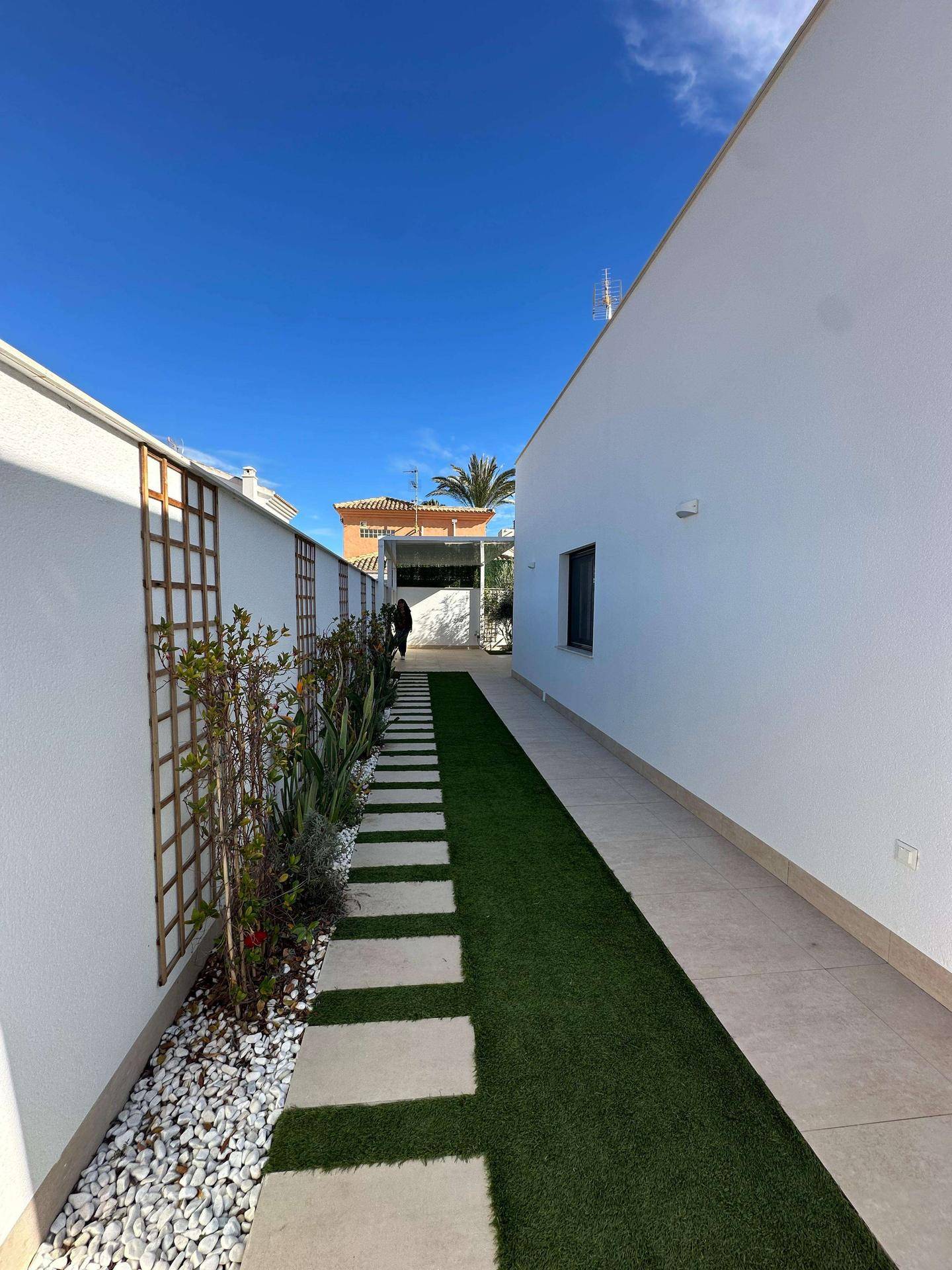 Schmaler Gartenweg mit Kunstrasen, Trittplatten und mediterraner Bepflanzung.