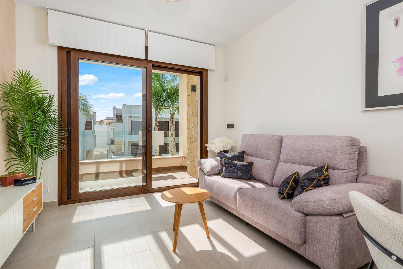 Helles Wohnzimmer mit bequemem Sofa und großer Schiebetür, die viel Tageslicht hereinlässt.