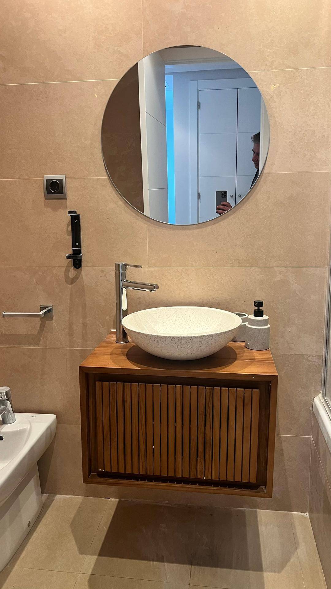 Modernes Badezimmer mit Aufsatzwaschbecken, Holzunterschrank und rundem Spiegel.