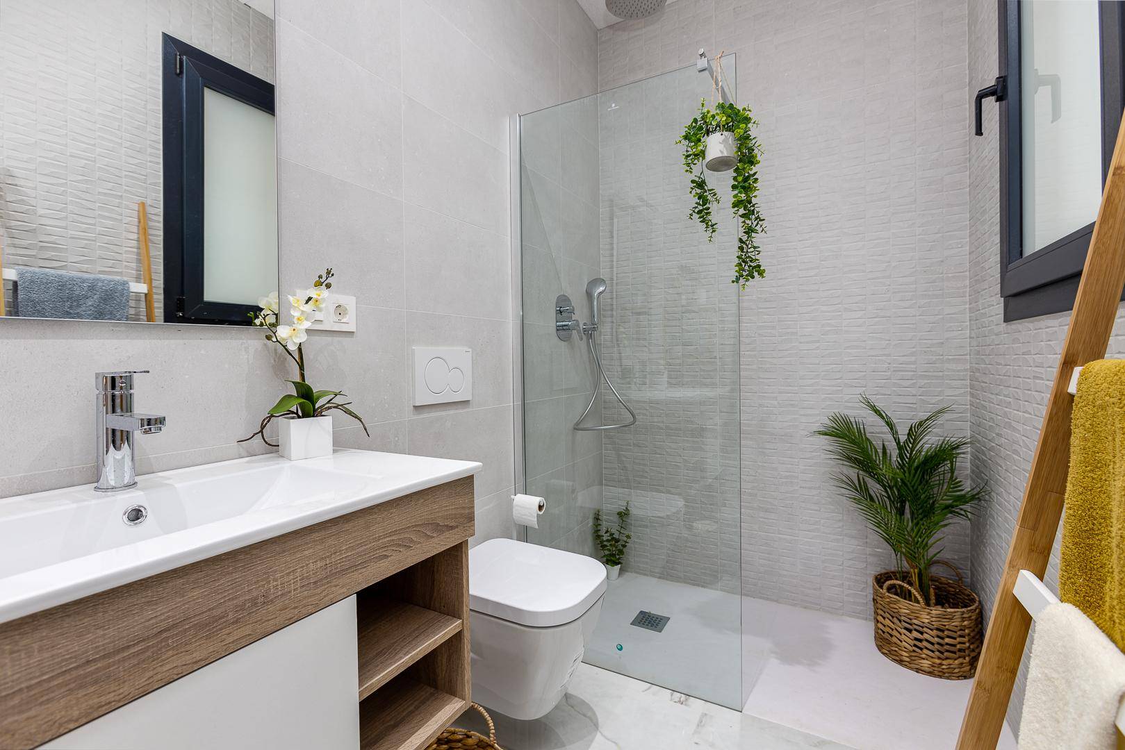 Helles Badezimmer mit bodengleicher Dusche, modernem Waschtisch und Fenster.