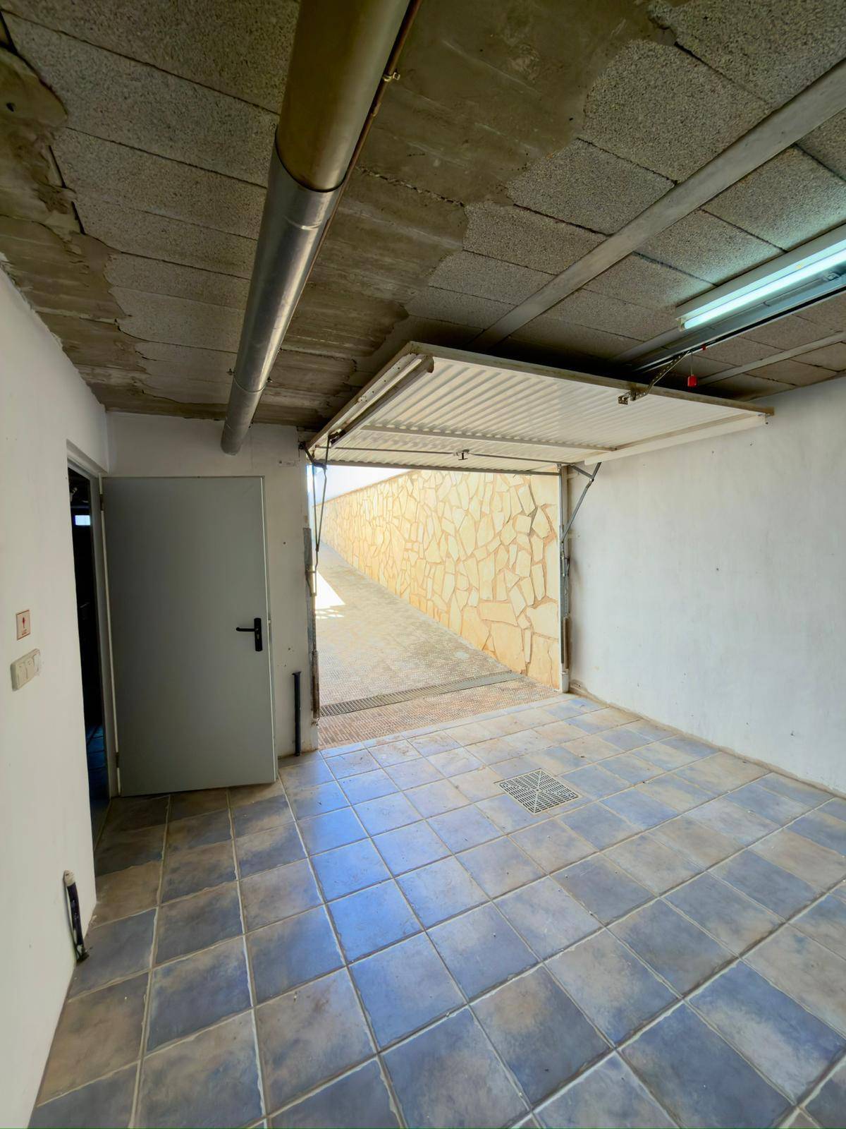 Geräumige Garage mit Fliesenboden und Zugang zur Auffahrt.