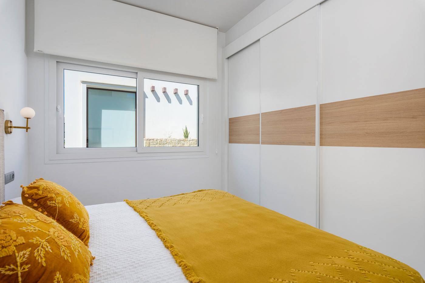 Schlafzimmer mit integriertem Schrank und Fenster, das den Blick auf die Außenfassade freigibt.