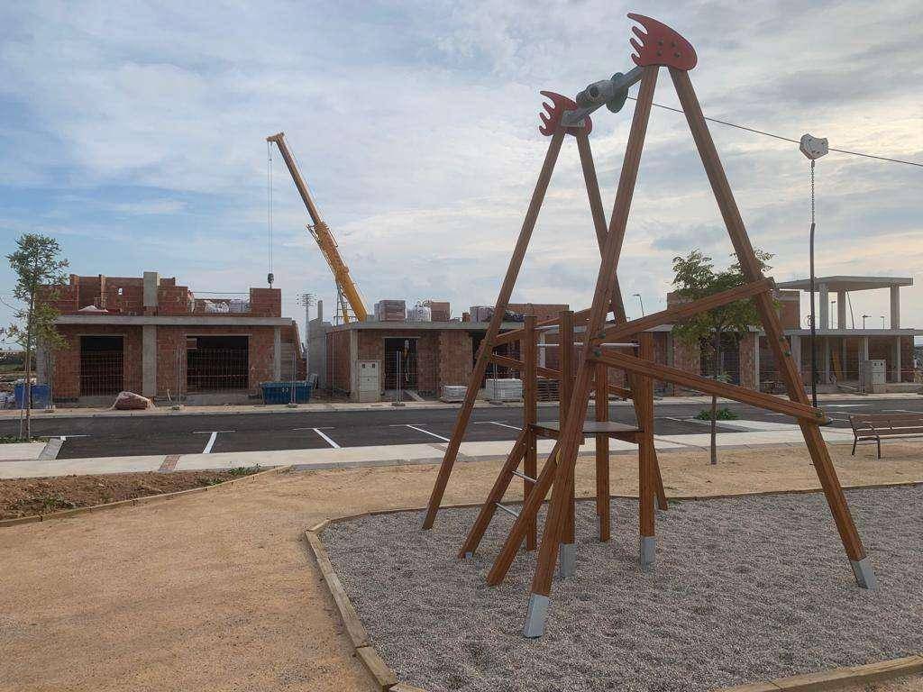 Spielplatz mit Schaukeln und Klettergerüst in einer neuen Wohnsiedlung.