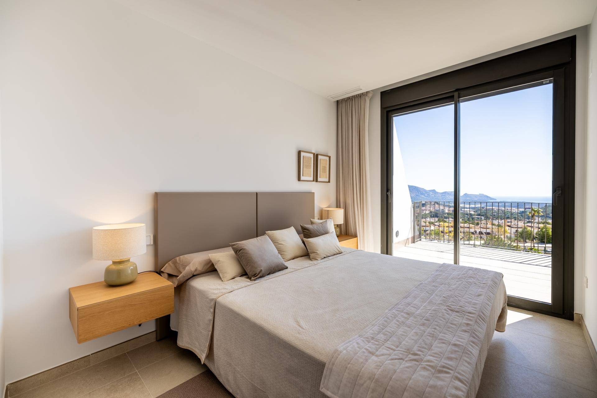 Geräumiges Schlafzimmer mit Doppelbett, Balkonzugang und Panoramablick auf das Meer und die Berge.