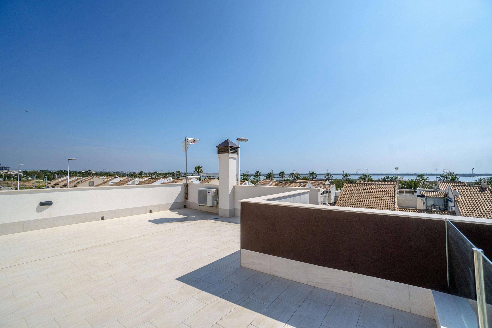 Geräumige Dachterrasse mit hellen Fliesen und weitem Blick über die Landschaft und das Meer.
