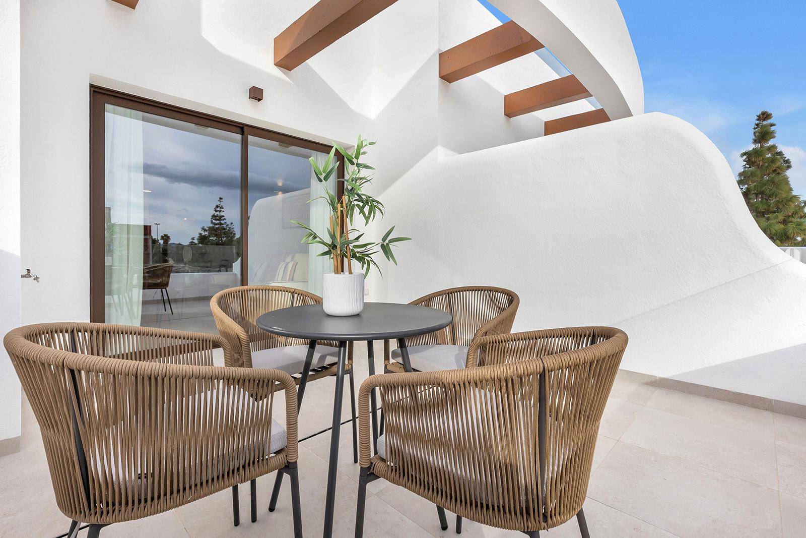 Gemütlicher Balkon mit Rattanmöbeln und einer Pergola, ideal für entspannte Stunden im Freien.
