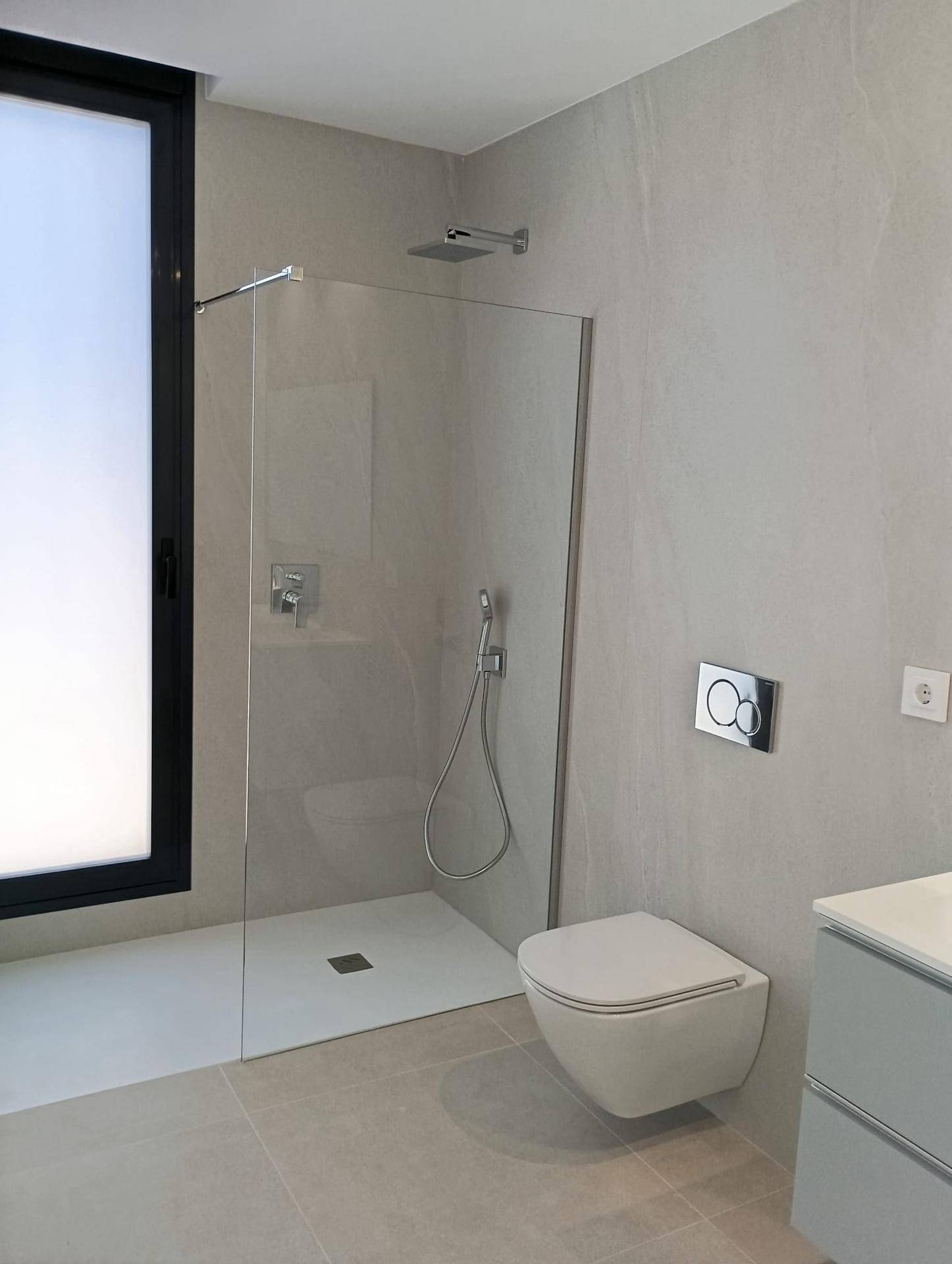 Modernes Badezimmer mit ebenerdiger Dusche, Wand-WC und großem Fenster für Tageslicht.
