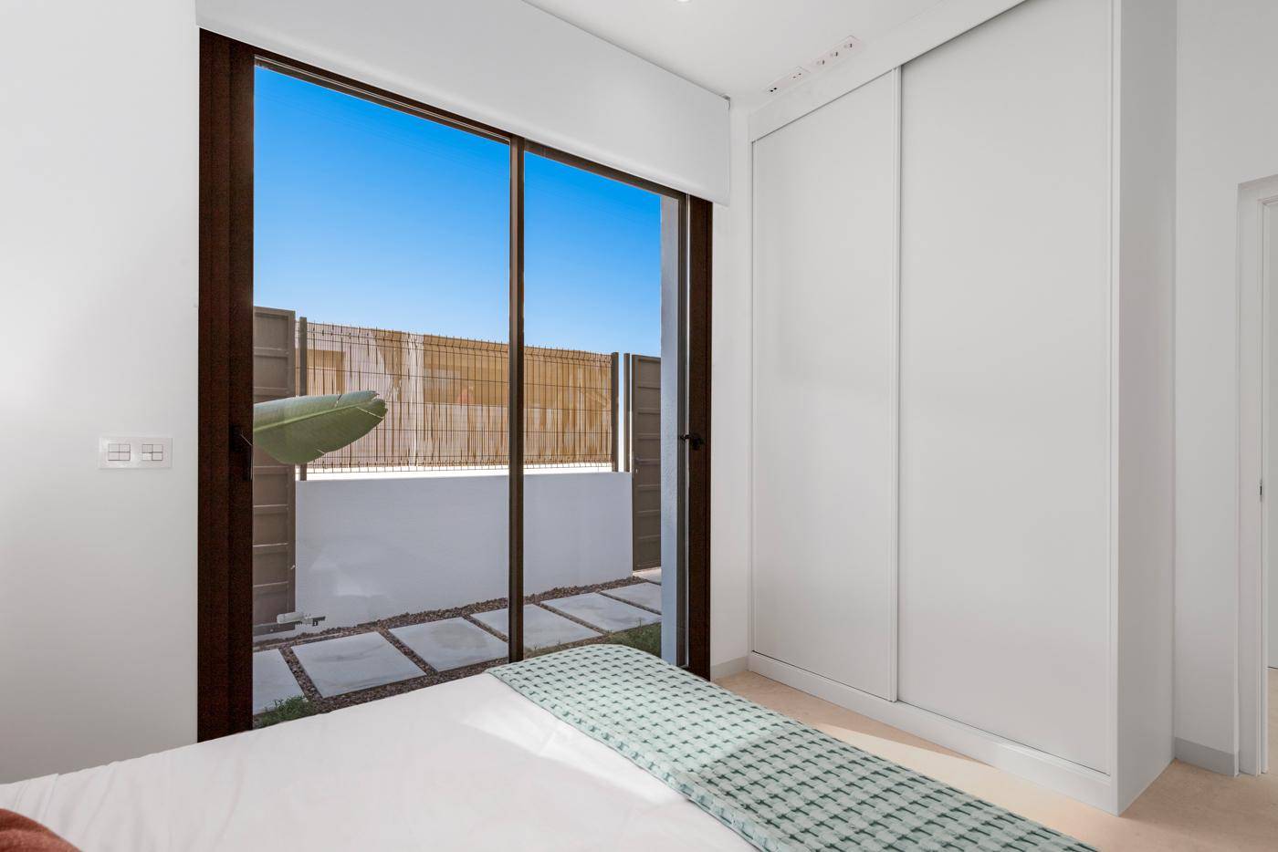 Schlafzimmer mit großen Schiebetüren, Einbauschränken und Blick auf den privaten Außenbereich.