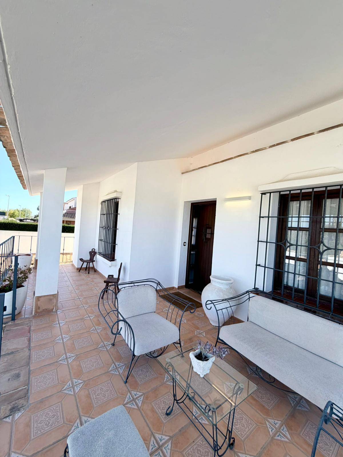 Gemütliche überdachte Terrasse mit Sitzgelegenheiten und traditionellen Bodenfliesen.