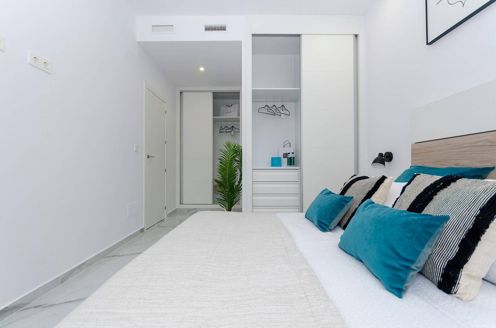 Komfortables Schlafzimmer mit Doppelbett, blauen Akzenten und praktischem Einbauschrank.