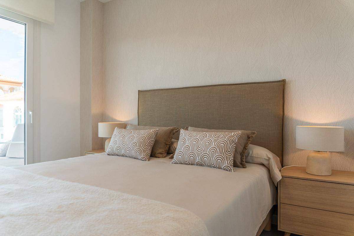 Detailansicht eines Doppelbettes mit Nachttischen und modernen Lampen im Schlafzimmer.