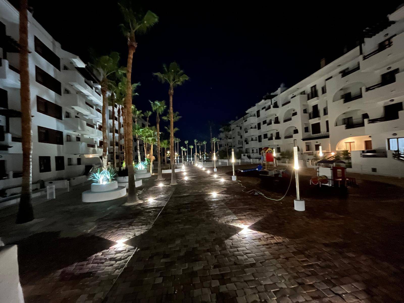 Beleuchteter Außenbereich der Apartmentanlage bei Nacht mit Palmen und Wegen.