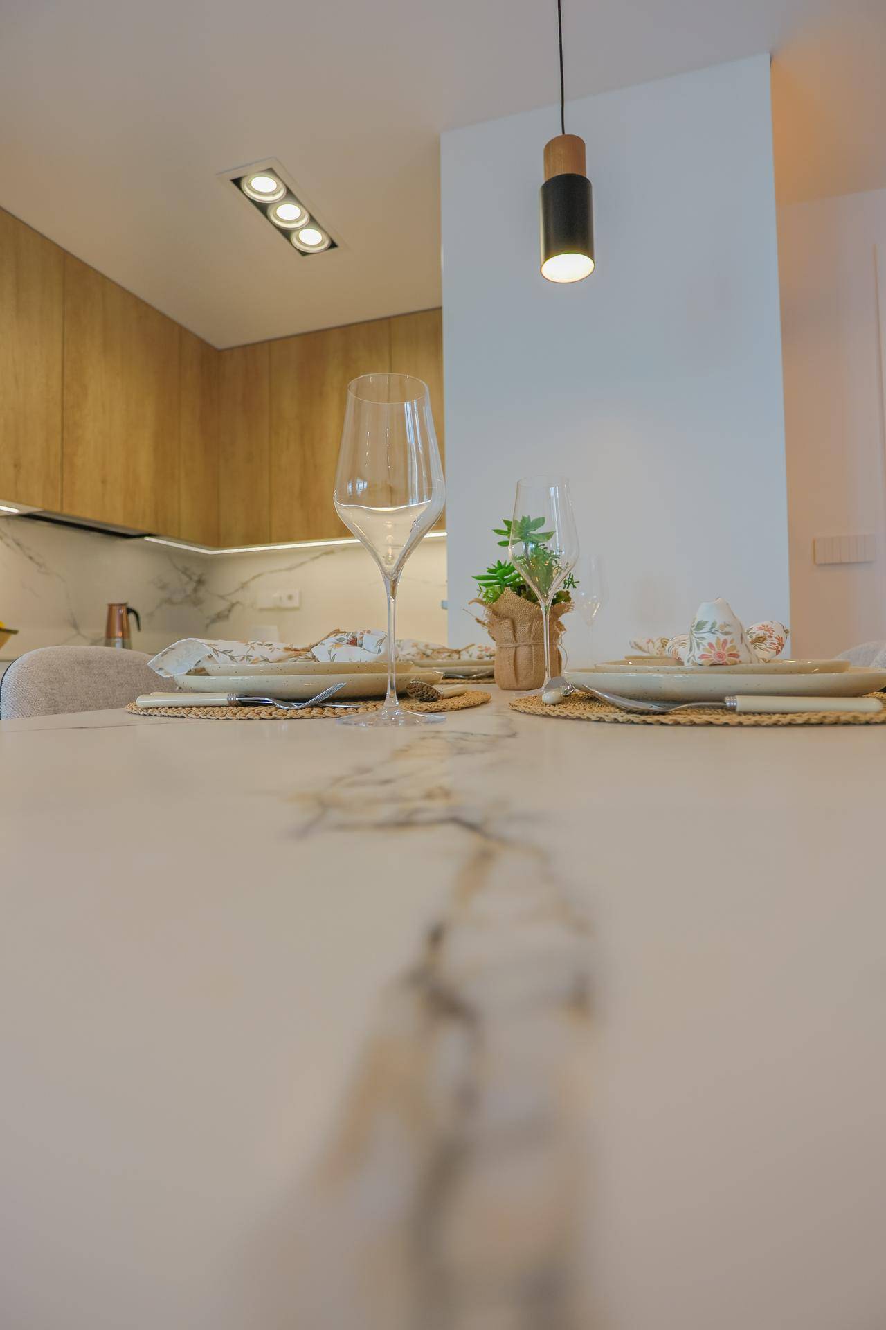 Modern gedeckter Esstisch mit eleganten Gläsern und Blick auf die offene Holzküche.