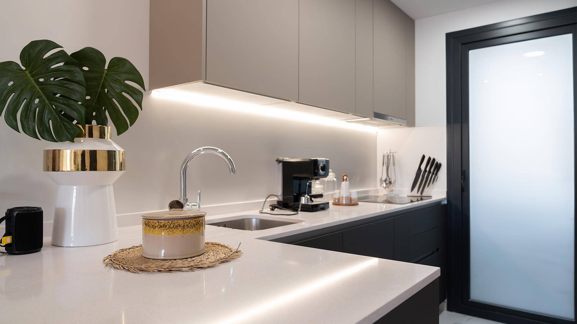 Moderne Küchenzeile mit heller Arbeitsplatte, Spüle und Kaffeemaschine.