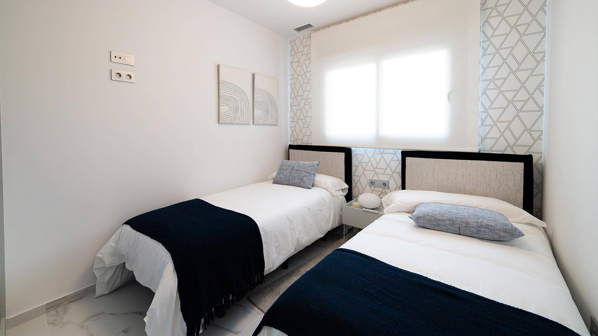Helles Schlafzimmer mit zwei Einzelbetten, minimalistischer Einrichtung und Fenster.