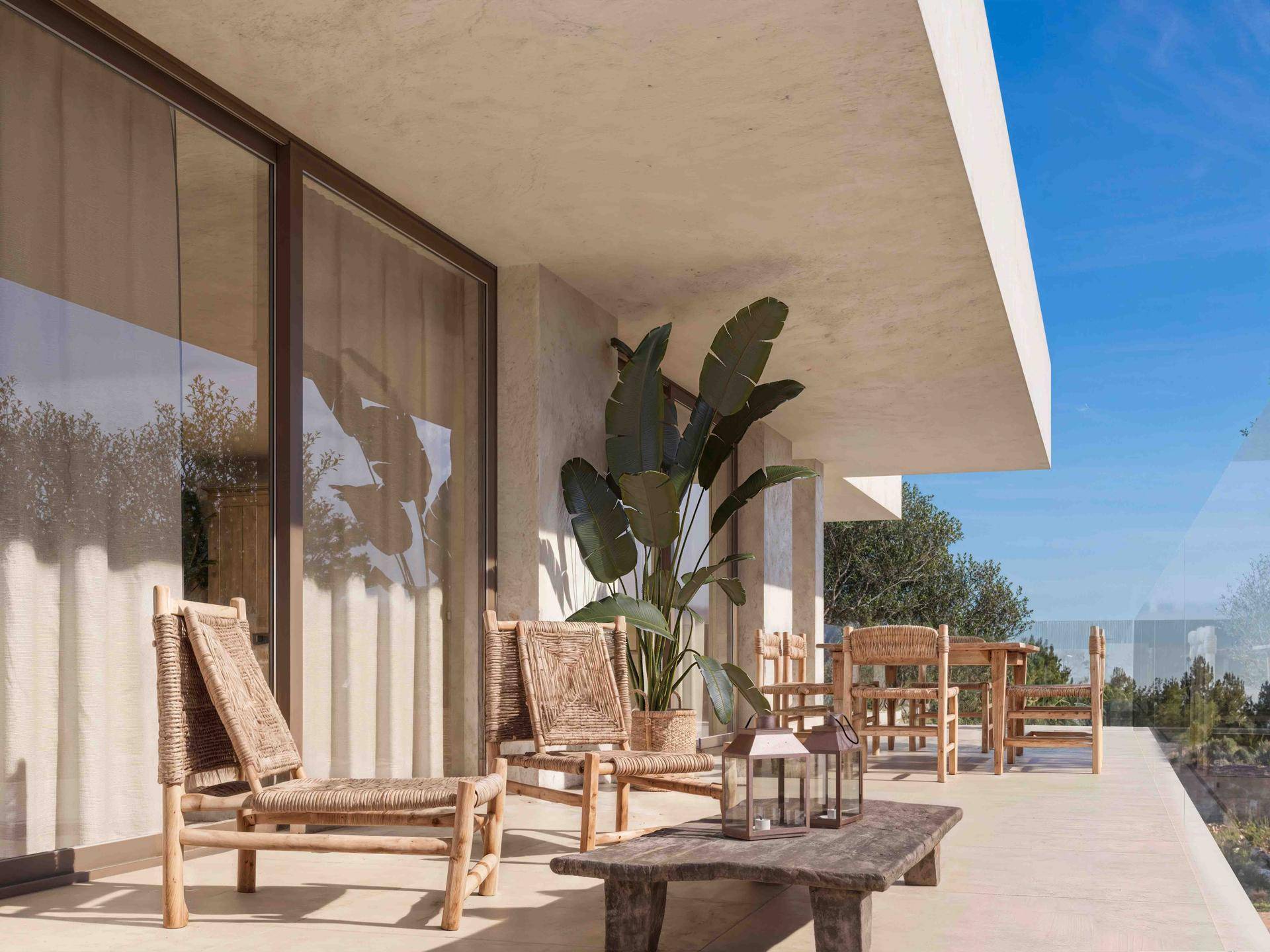 Sonniger Balkon mit Rattanmöbeln und Blick ins Grüne, ideal für entspannte Stunden im Freien.