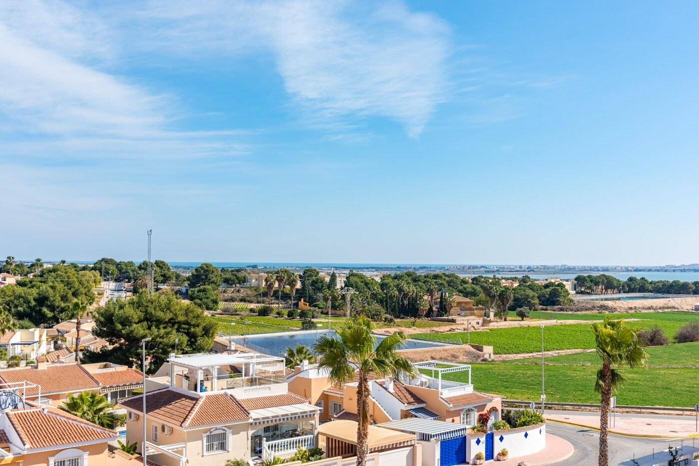 Weitläufiger Blick über die Wohngegend, grüne Felder und das Meer in der Ferne.