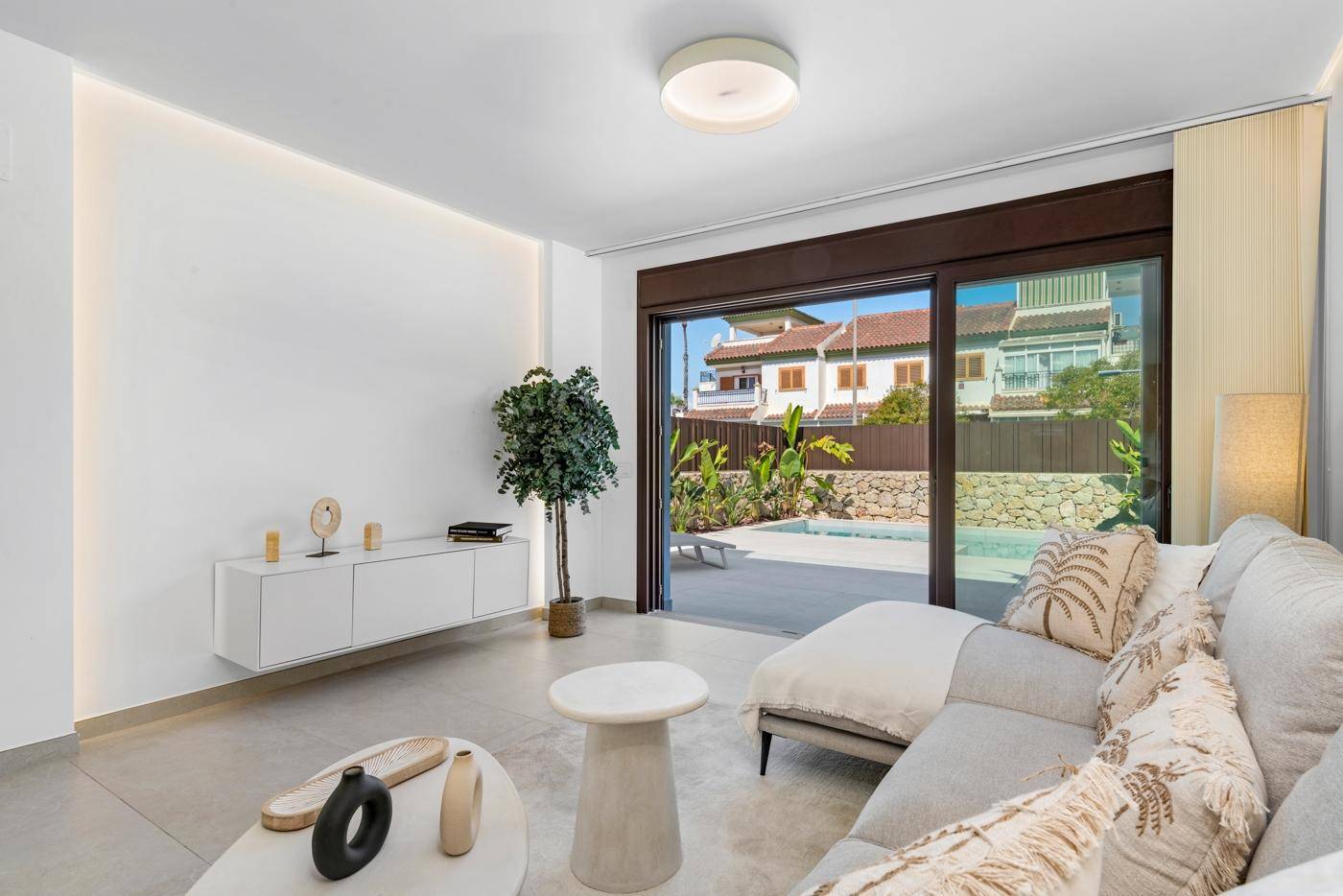 Gemütliches Wohnzimmer mit großen Schiebetüren, die den Blick auf den Pool und die Terrasse freigeben.