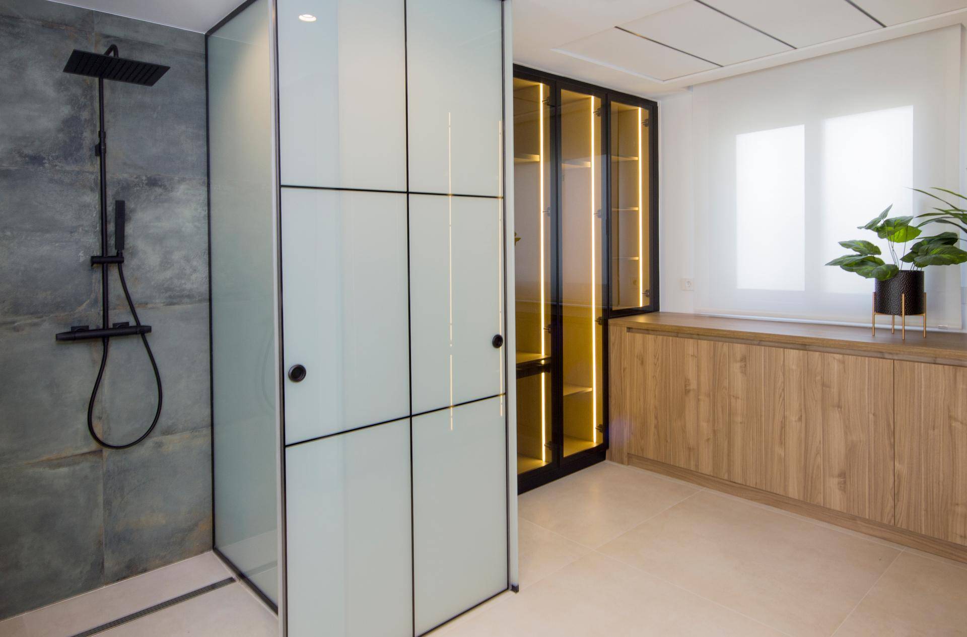 Modernes Badezimmer mit begehbarer Dusche und beleuchtetem Kleiderschrank.