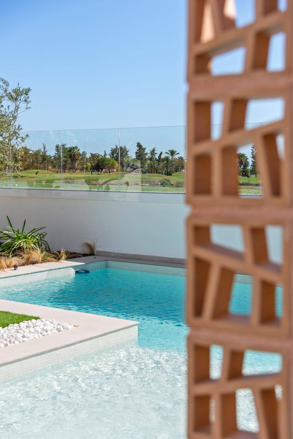 Detailansicht des Pools mit dekorativer Trennwand und Blick auf den Golfplatz.
