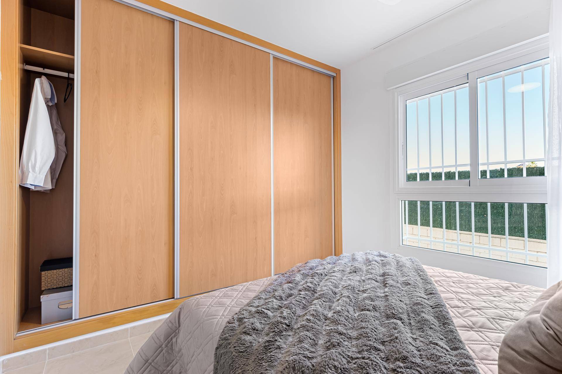 Schlafzimmer mit praktischem Einbauschrank und Schiebetüren aus hellem Holz.