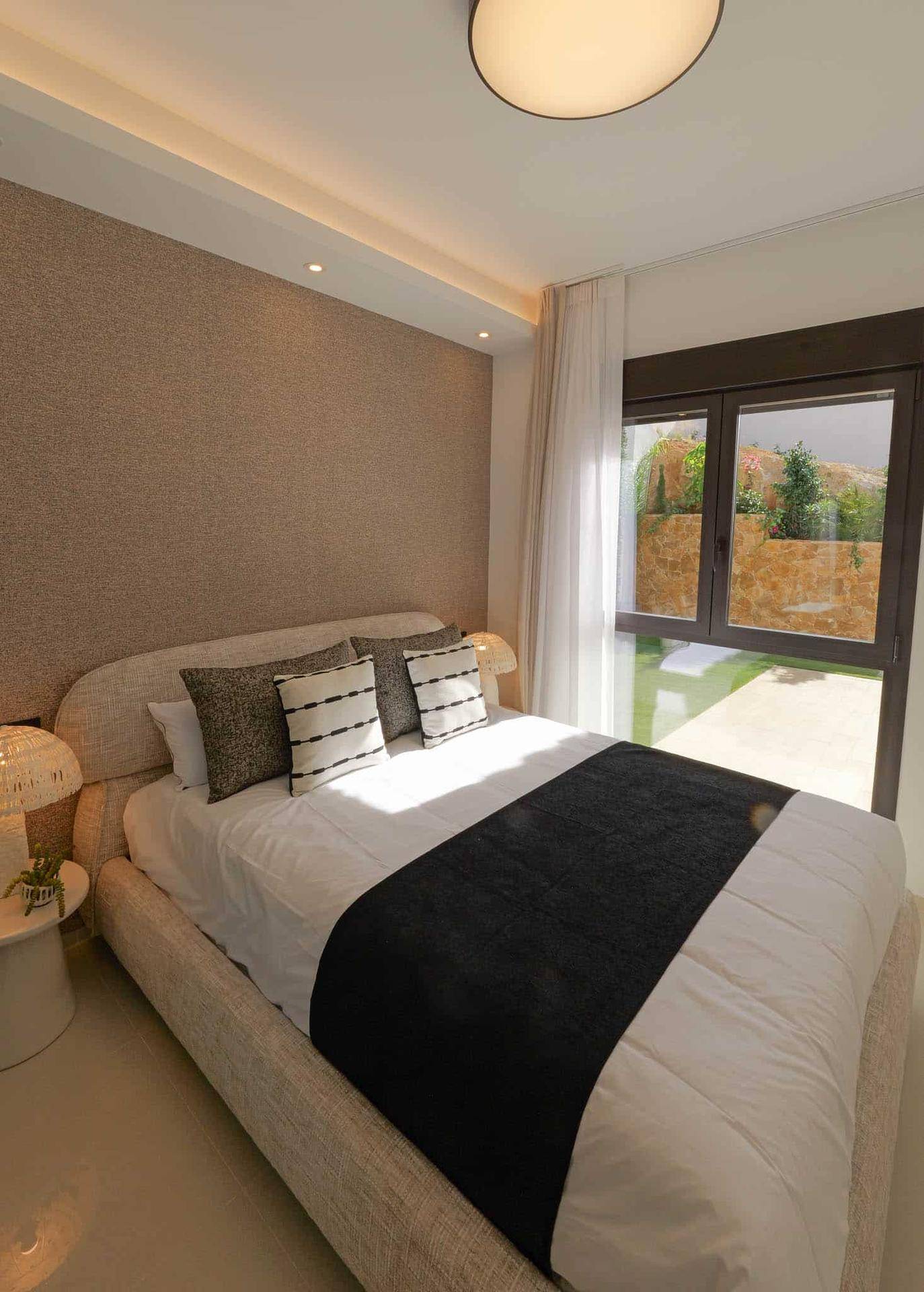Helles Schlafzimmer mit beigem Bett und Fenster zum Garten, bietet eine ruhige Atmosphäre.