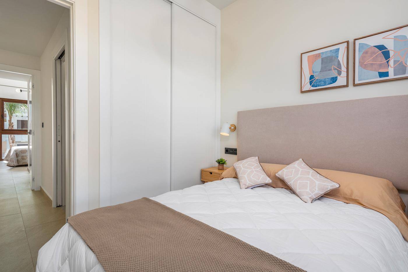 Schlafzimmer mit Doppelbett und integriertem Kleiderschrank, hell und funktional eingerichtet.