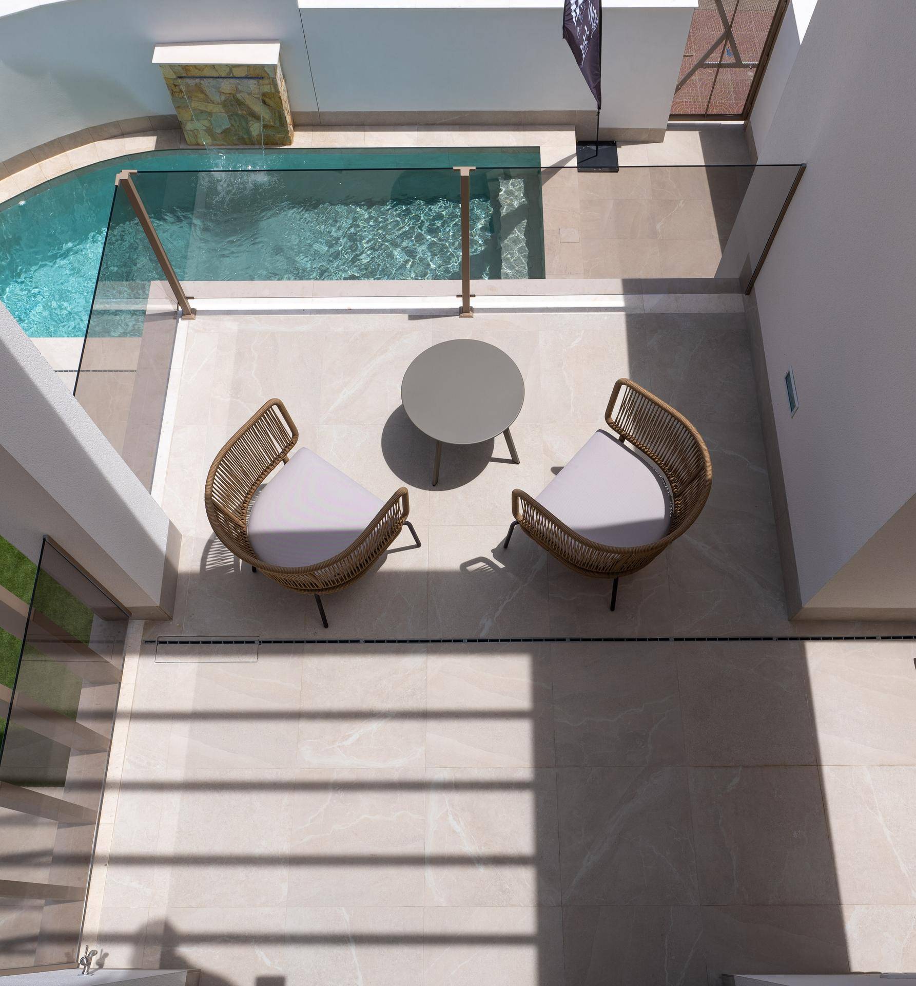 Terrasse mit modernen Outdoor-Möbeln und Blick auf den privaten Pool und die umliegende Bebauung.