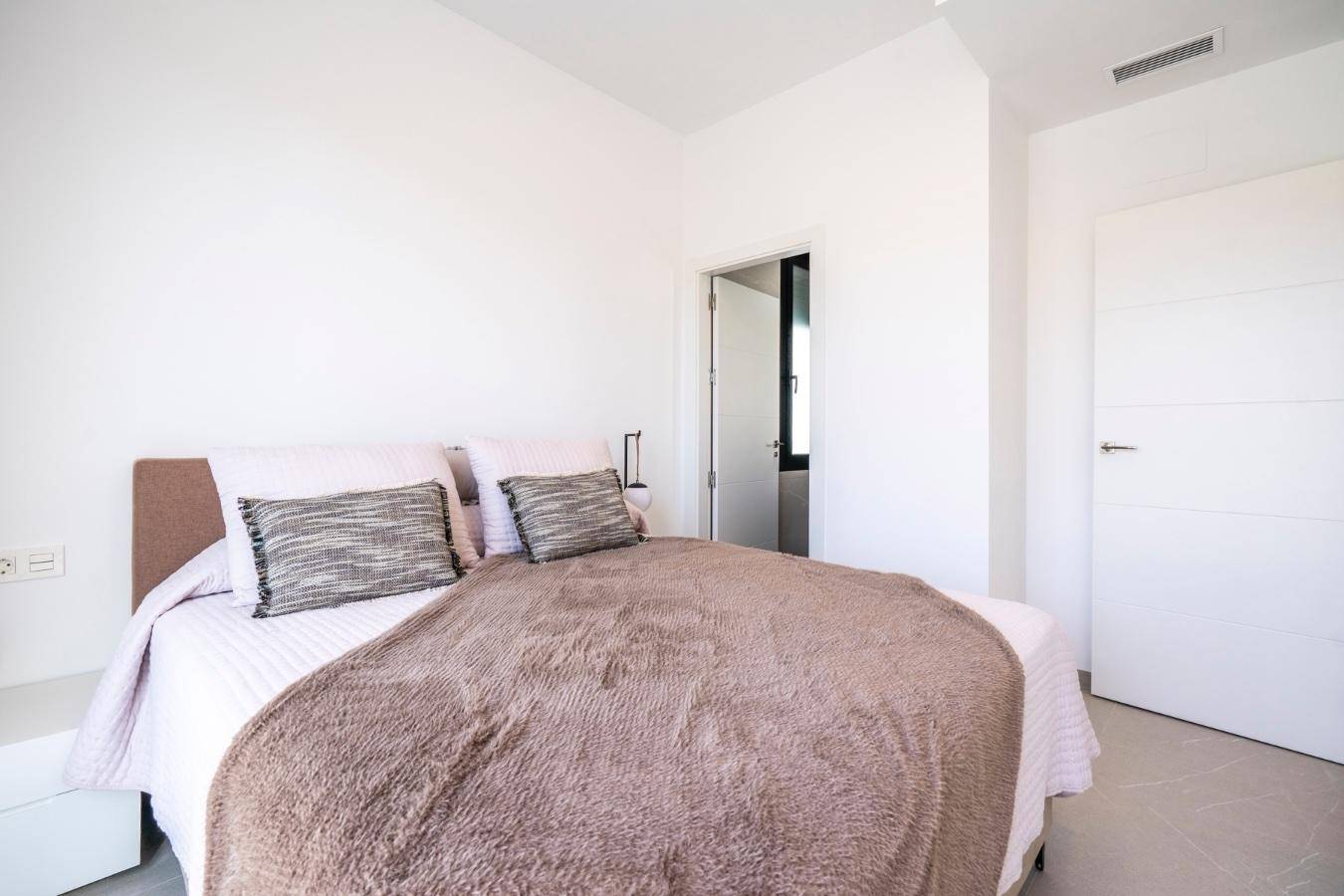 Ruhiges Schlafzimmer mit Doppelbett, weißen Wänden und modernem Fliesenboden für erholsame Nächte.