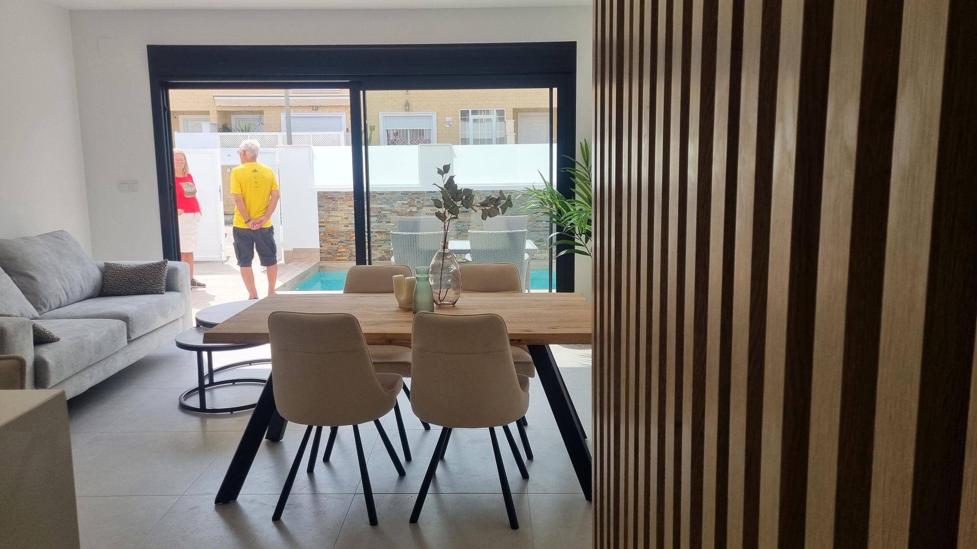 Heller Wohn- und Essbereich mit modernen Möbeln und Blick auf den Außenbereich mit Pool.