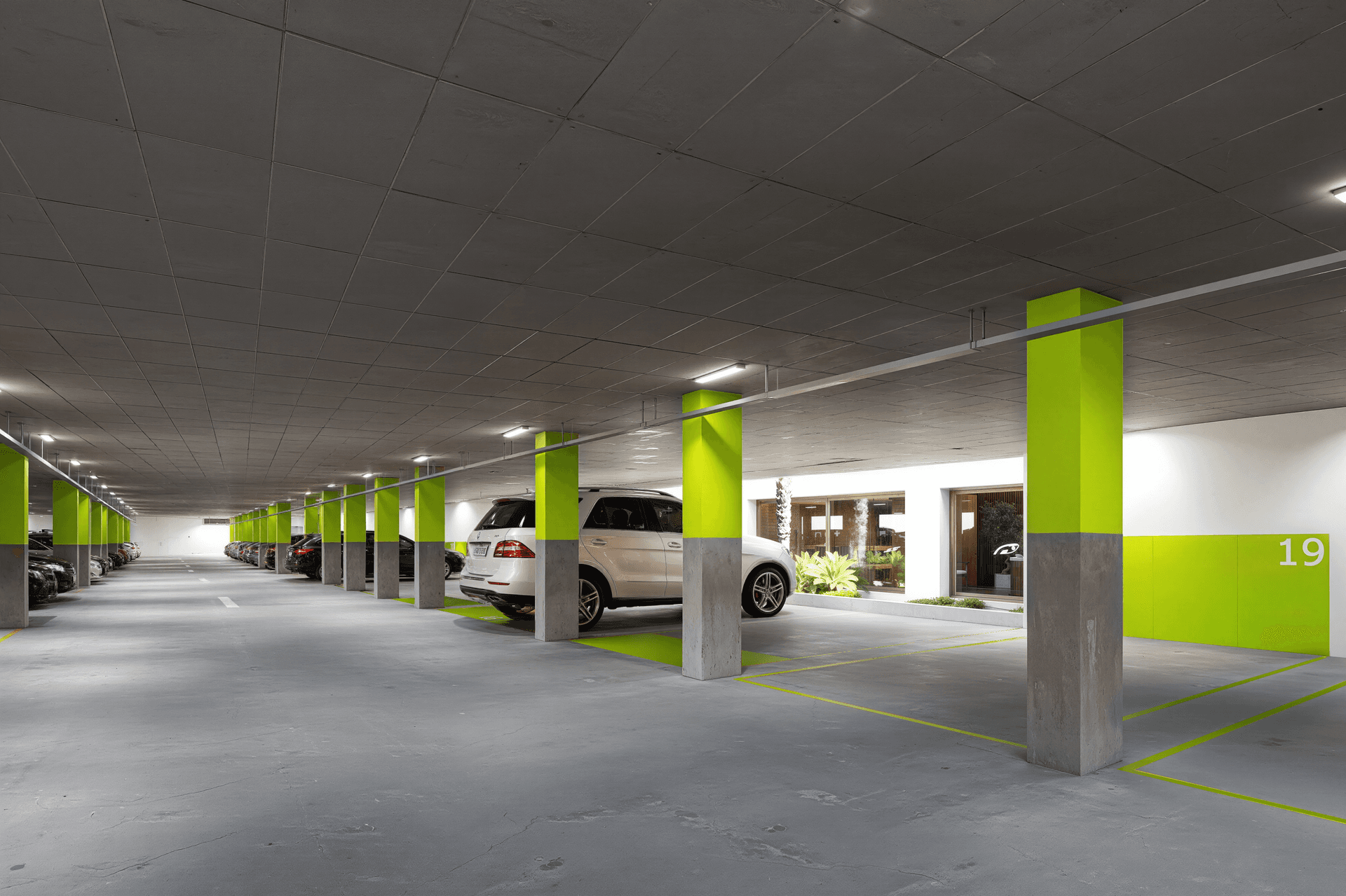 Helle Tiefgarage mit markierten Parkplätzen und modernen Fahrzeugen.