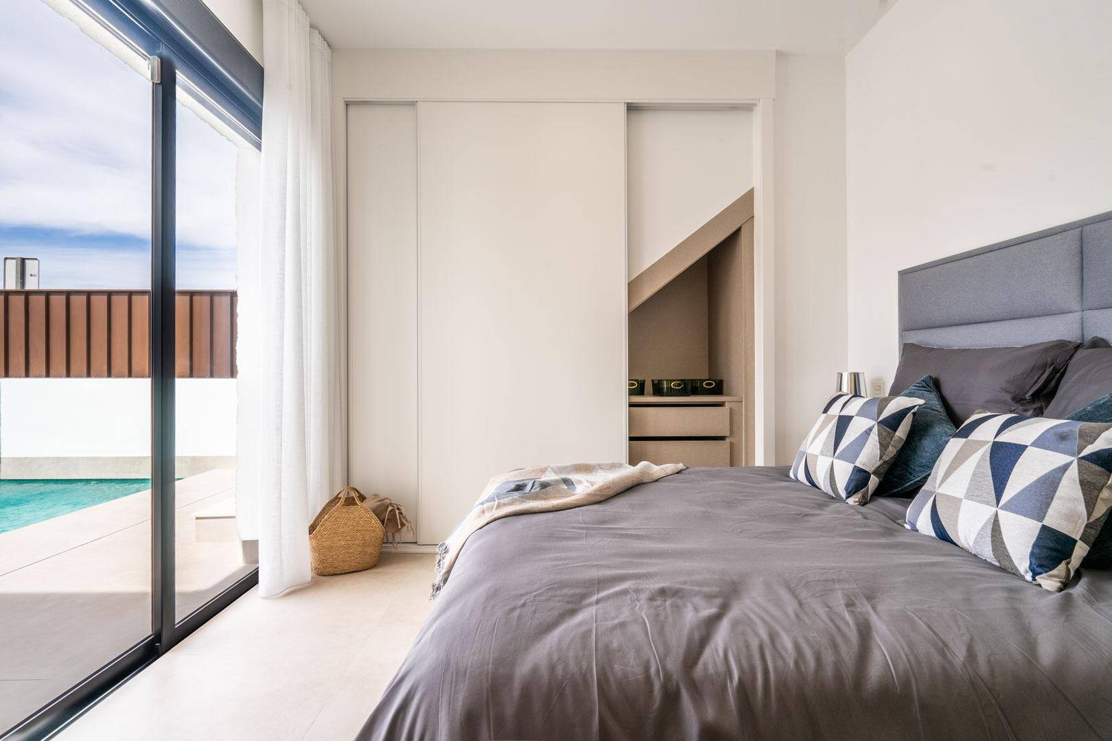Schlafzimmer mit Einbauschrank, Poolblick und großen Fenstern.