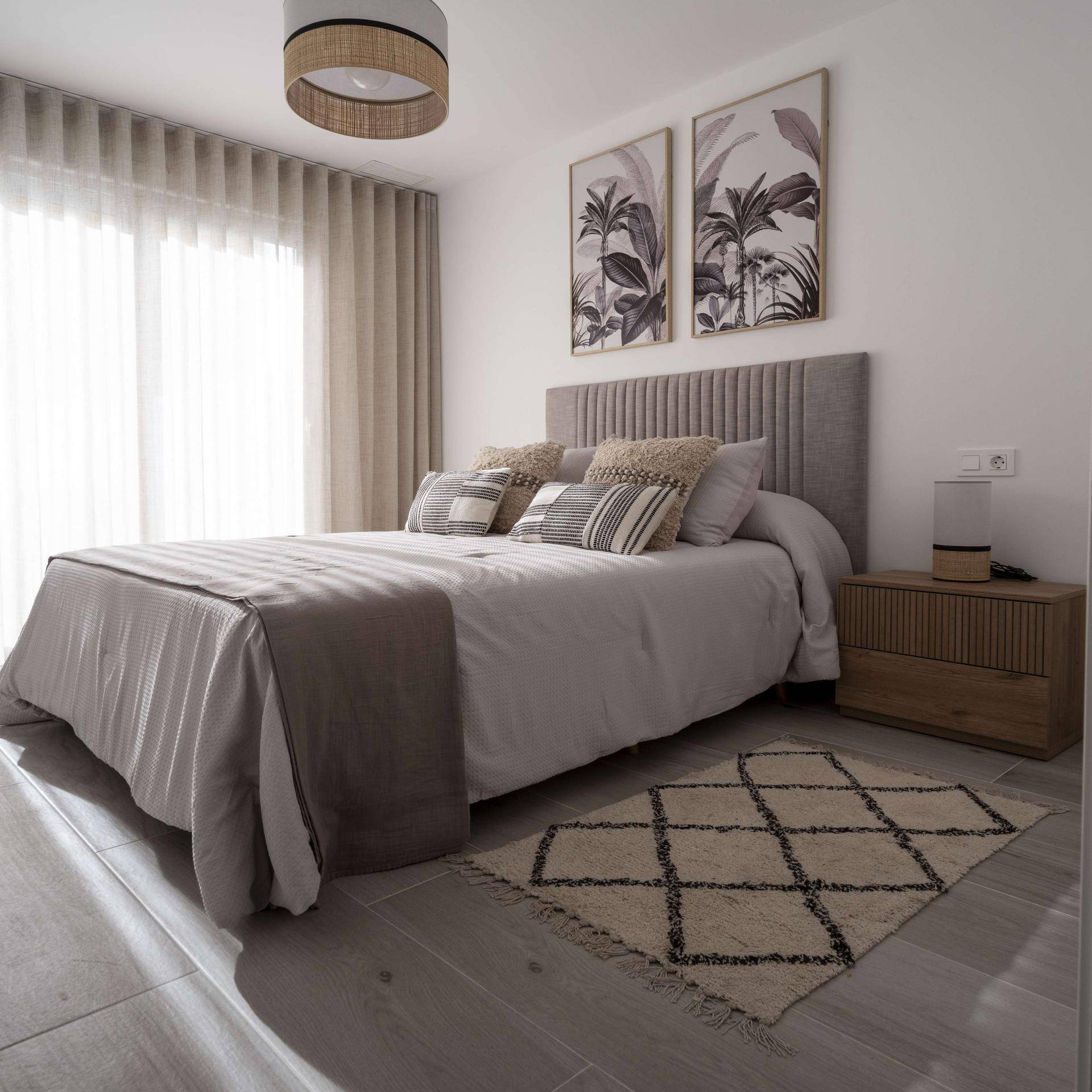 Helles Schlafzimmer mit Doppelbett, stilvoller Einrichtung und Zugang zum Balkon.