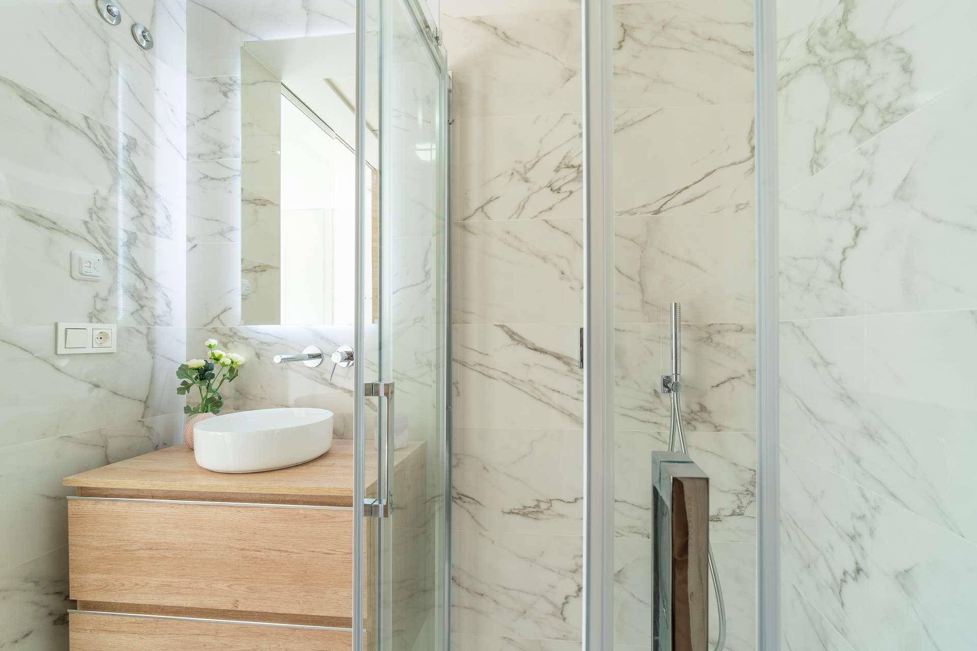 Modernes Badezimmer mit Marmorfliesen, Holzwaschtisch und begehbarer Dusche.